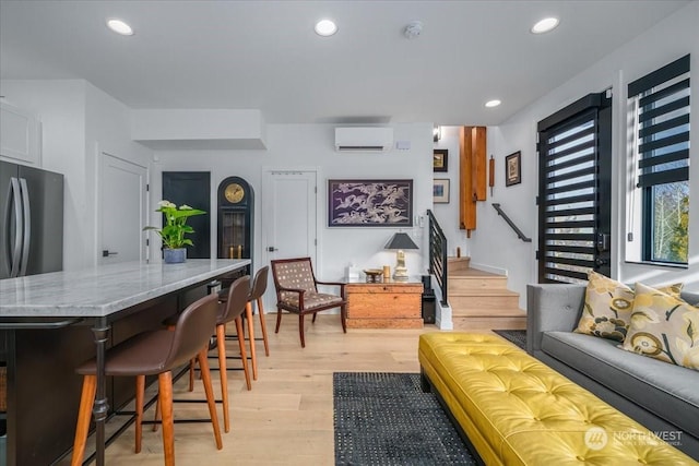 interior space with a kitchen breakfast bar, a wall mounted AC, and light hardwood / wood-style floors