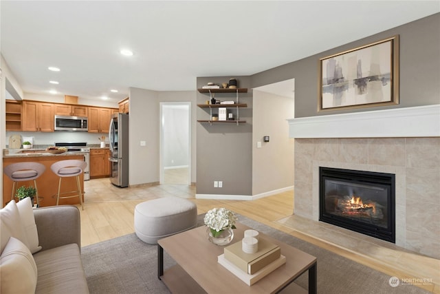 living room featuring a tile fireplace and light wood-type flooring