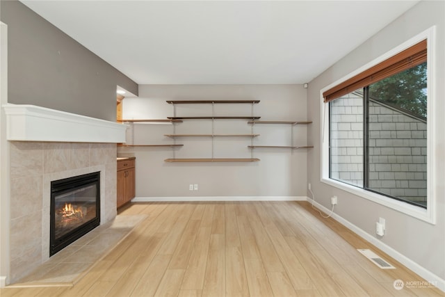 unfurnished living room featuring light hardwood / wood-style floors and a tile fireplace