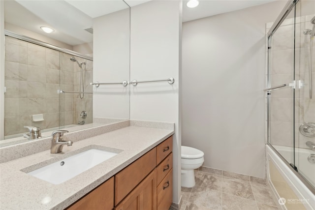 full bathroom with vanity, bath / shower combo with glass door, and toilet