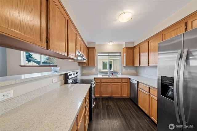 kitchen featuring dark wood-type flooring, appliances with stainless steel finishes, light stone countertops, and sink