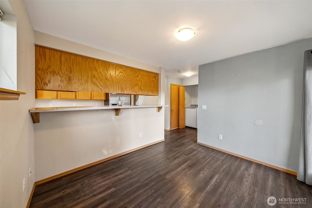 kitchen featuring dark hardwood / wood-style floors, stainless steel fridge, kitchen peninsula, and a breakfast bar