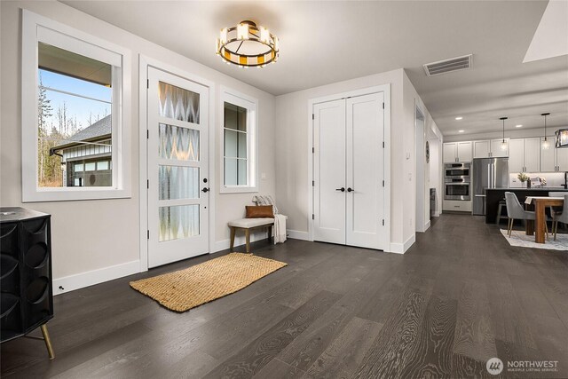 entrance foyer with baseboards, visible vents, and dark wood finished floors