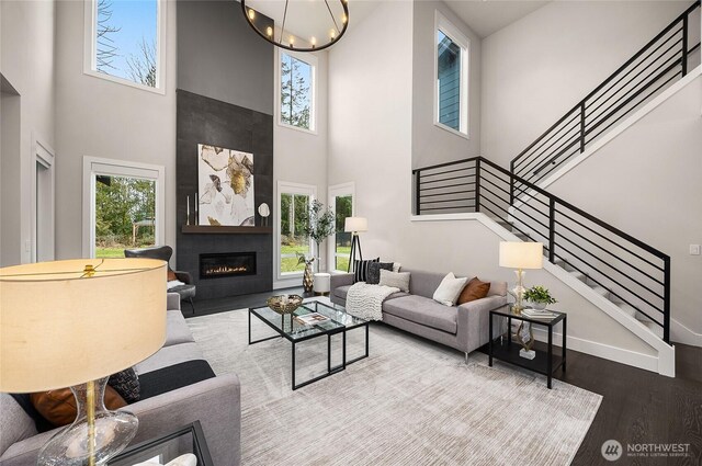 living room featuring a healthy amount of sunlight, light wood-style flooring, stairway, and a glass covered fireplace