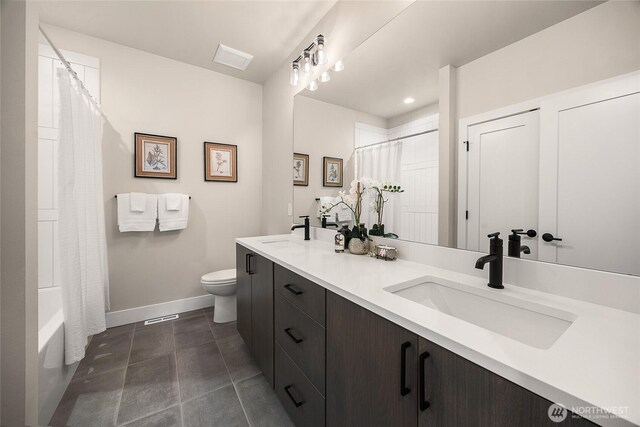 full bath featuring double vanity, baseboards, toilet, and a sink