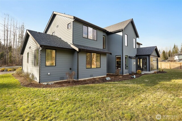 rear view of property with a shingled roof, a lawn, a sunroom, crawl space, and fence