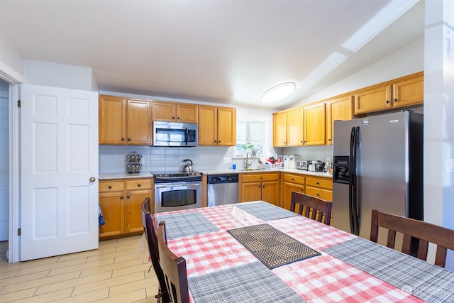 kitchen with tasteful backsplash, lofted ceiling, appliances with stainless steel finishes, and sink