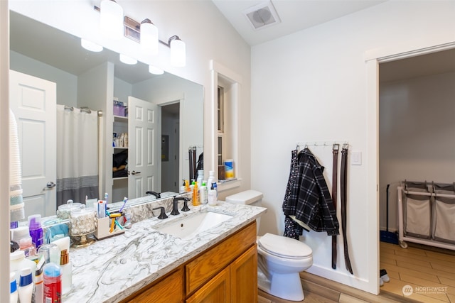 bathroom with vanity, toilet, and hardwood / wood-style floors