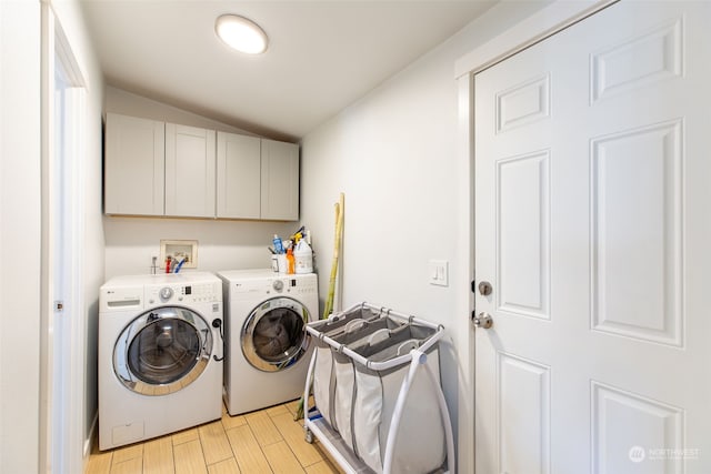 washroom featuring cabinets, washing machine and dryer, and light wood-type flooring