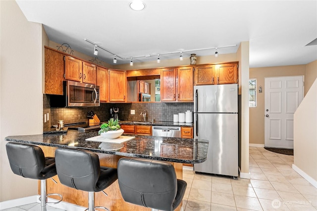 kitchen with appliances with stainless steel finishes, a kitchen breakfast bar, tasteful backsplash, and kitchen peninsula