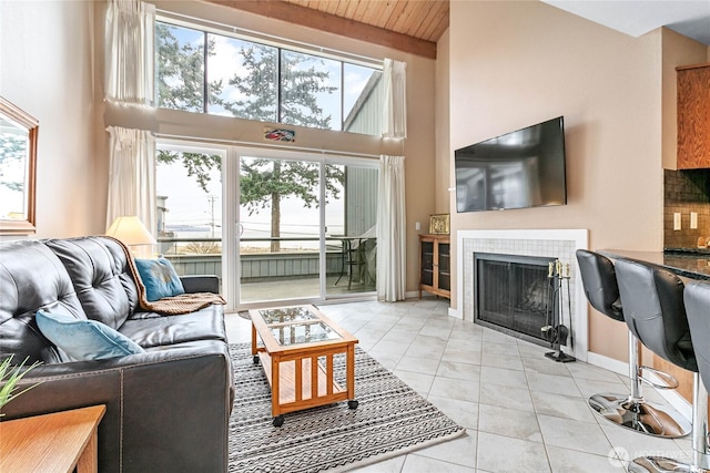 living room with a fireplace, a towering ceiling, beam ceiling, wooden ceiling, and light tile patterned floors