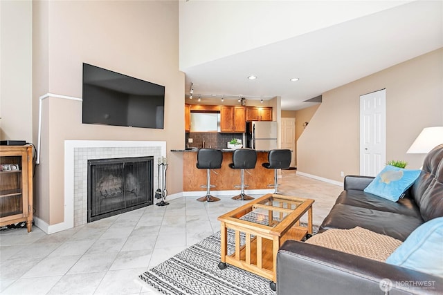 living room featuring a tile fireplace and rail lighting