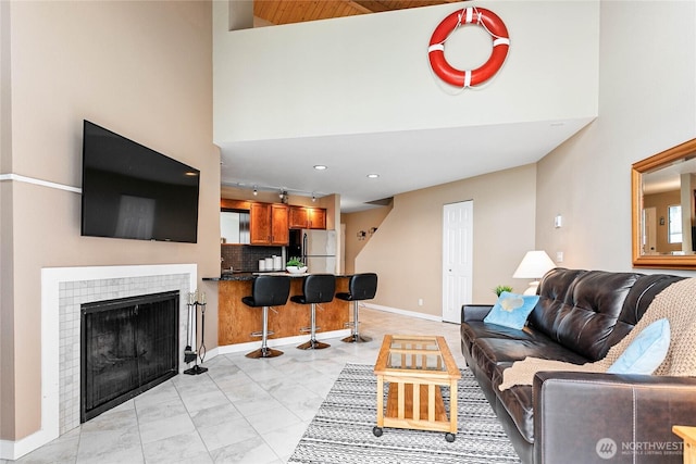 living room featuring a fireplace, track lighting, and a high ceiling