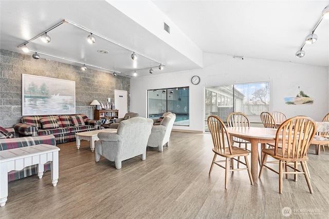 dining room featuring lofted ceiling, rail lighting, and hardwood / wood-style floors