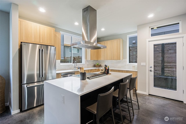 kitchen featuring a breakfast bar area, island range hood, a center island, light brown cabinets, and stainless steel appliances