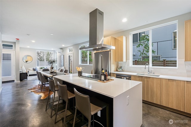 kitchen featuring sink, high end fridge, island range hood, a kitchen island, and decorative backsplash