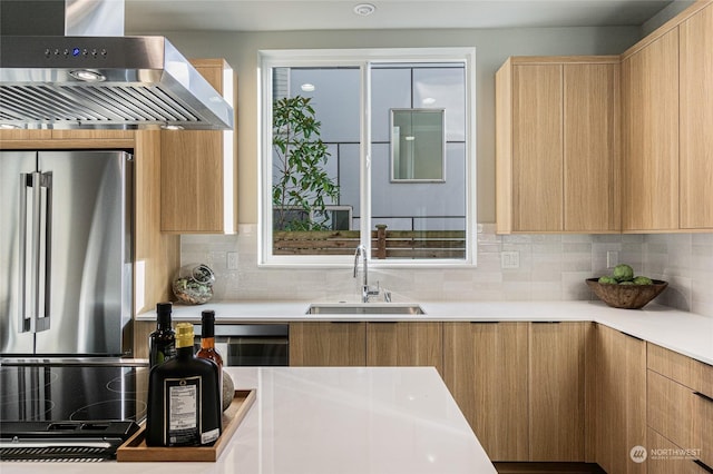 kitchen with sink, backsplash, range hood, and stainless steel refrigerator