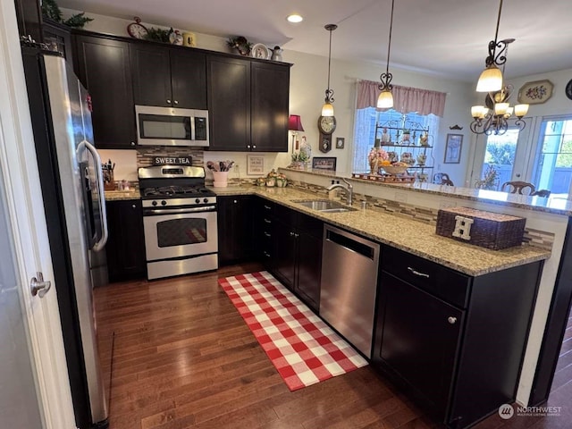 kitchen featuring stainless steel appliances, sink, pendant lighting, and kitchen peninsula