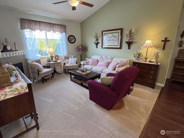 living room featuring ceiling fan, a fireplace, light hardwood / wood-style floors, and vaulted ceiling