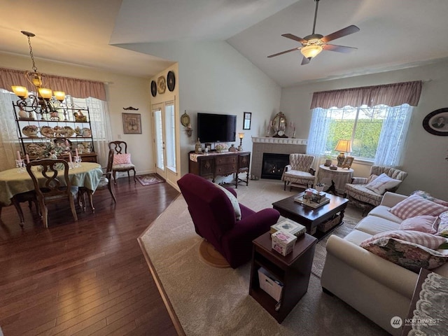 living room with dark wood-type flooring, ceiling fan with notable chandelier, and vaulted ceiling