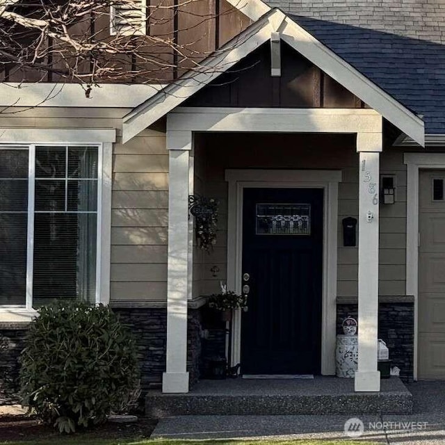 property entrance featuring a garage and stone siding