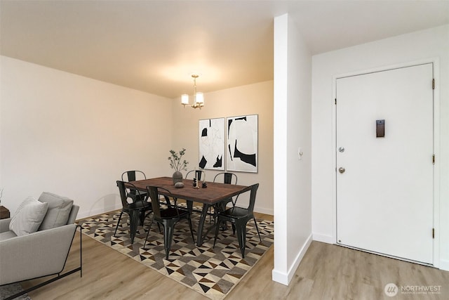 dining space featuring light wood-style floors, baseboards, and a chandelier
