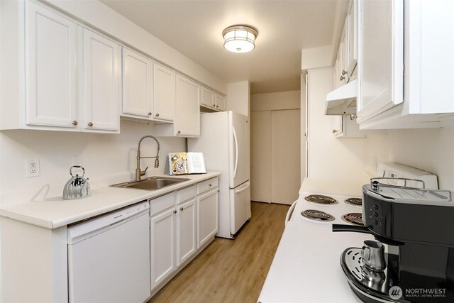 kitchen with white appliances, white cabinets, under cabinet range hood, and a sink