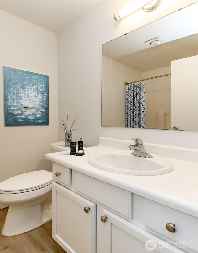 bathroom with vanity, a shower with curtain, toilet, and wood finished floors
