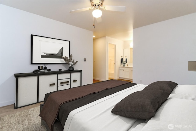 bedroom with ceiling fan, ensuite bathroom, and light wood-style floors