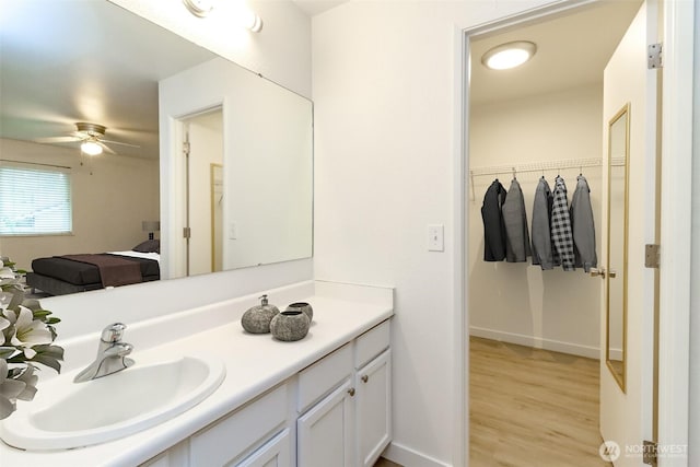 bathroom featuring vanity, a ceiling fan, wood finished floors, and a spacious closet