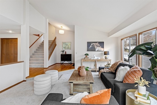 living room featuring baseboards, stairway, and vaulted ceiling