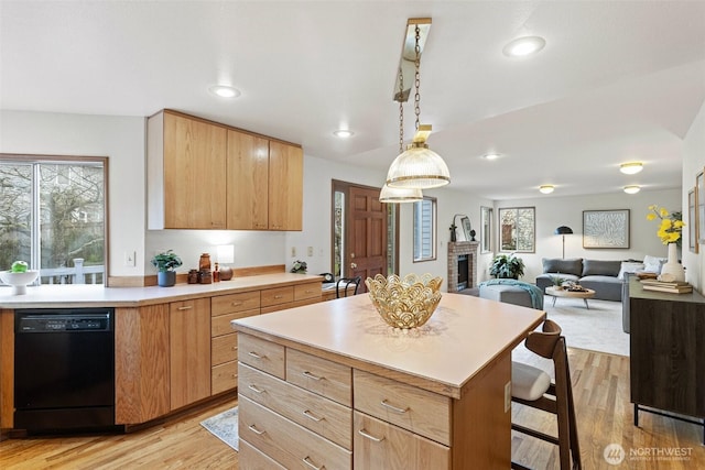 kitchen featuring dishwasher, a kitchen island, open floor plan, hanging light fixtures, and light countertops