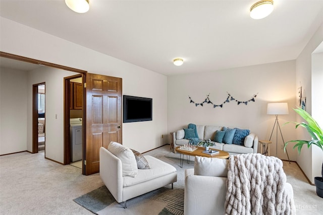 living room featuring washer / dryer, baseboards, and light colored carpet