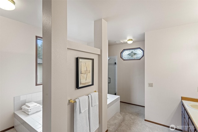 bathroom featuring a stall shower, baseboards, a garden tub, and vanity