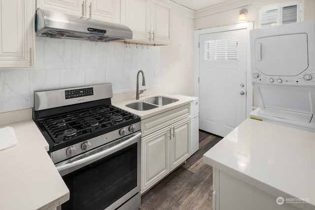 kitchen featuring stacked washer / dryer, sink, decorative backsplash, dark wood-type flooring, and stainless steel gas range