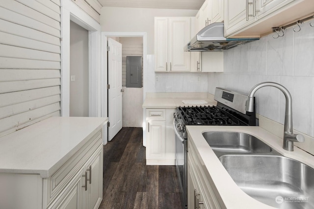 kitchen with sink, stainless steel gas range oven, dark hardwood / wood-style flooring, electric panel, and white cabinets