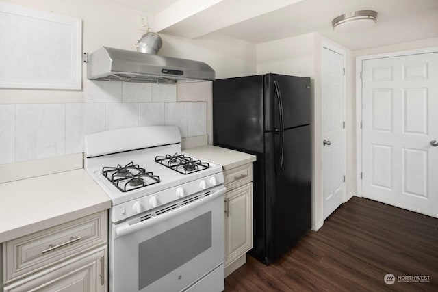 kitchen featuring black refrigerator, backsplash, dark hardwood / wood-style flooring, exhaust hood, and white range with gas stovetop