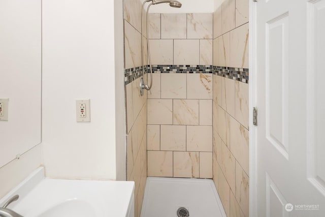 bathroom featuring tiled shower and sink