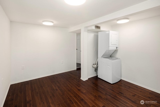 washroom with dark wood-type flooring and stacked washer / dryer