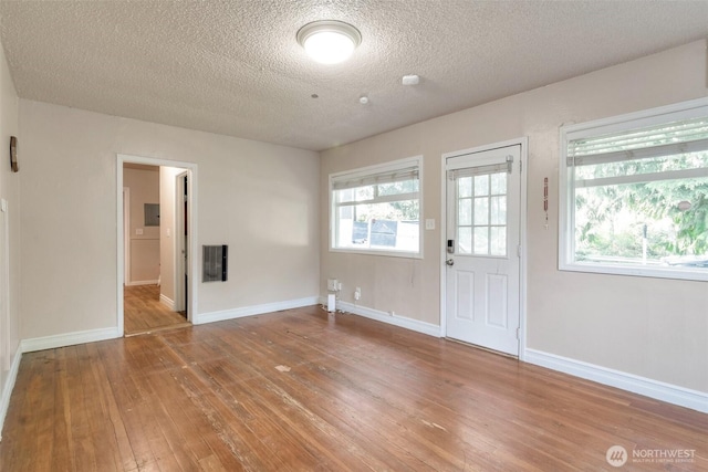 foyer entrance with hardwood / wood-style floors, baseboards, and a textured ceiling