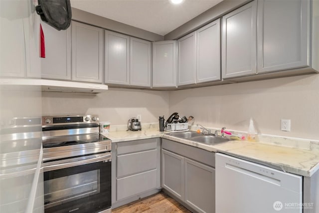 kitchen featuring gray cabinets, electric range, under cabinet range hood, light countertops, and white dishwasher
