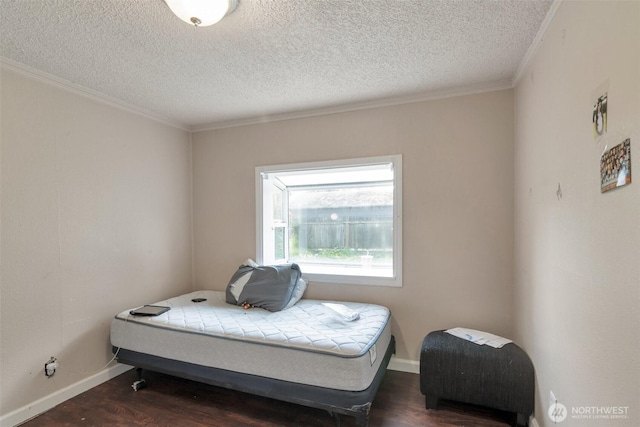 bedroom featuring a textured ceiling, wood finished floors, ornamental molding, and baseboards