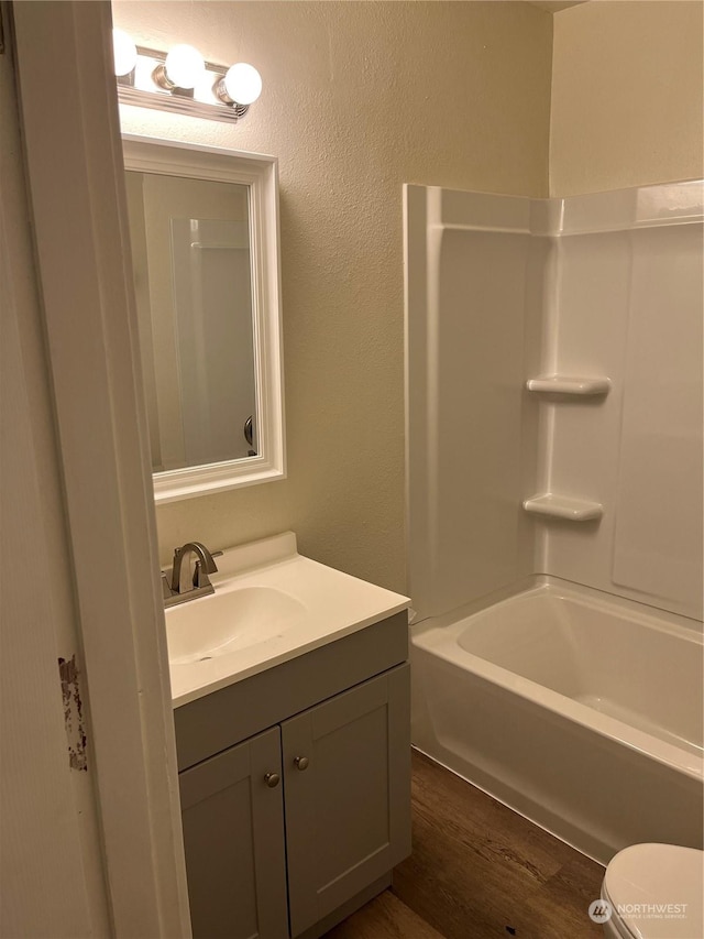 full bathroom featuring hardwood / wood-style flooring, vanity, bathtub / shower combination, and toilet