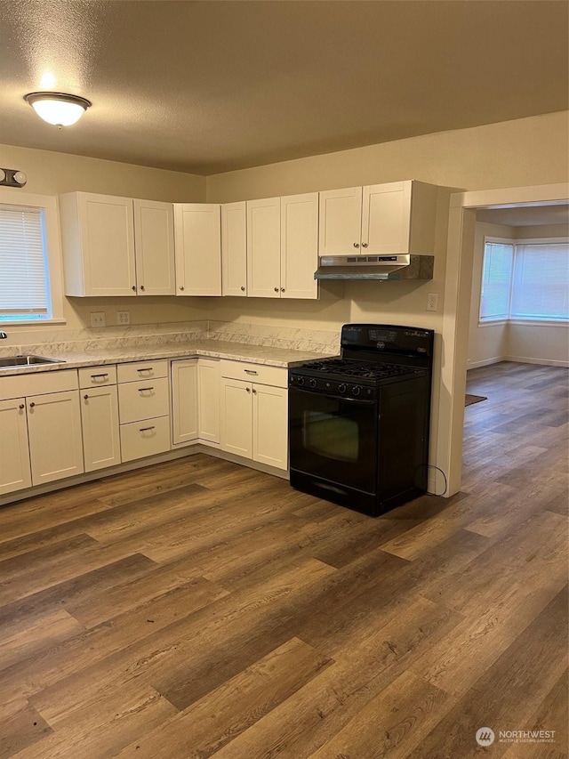 kitchen with sink, dark wood-type flooring, black range with gas cooktop, a textured ceiling, and white cabinets