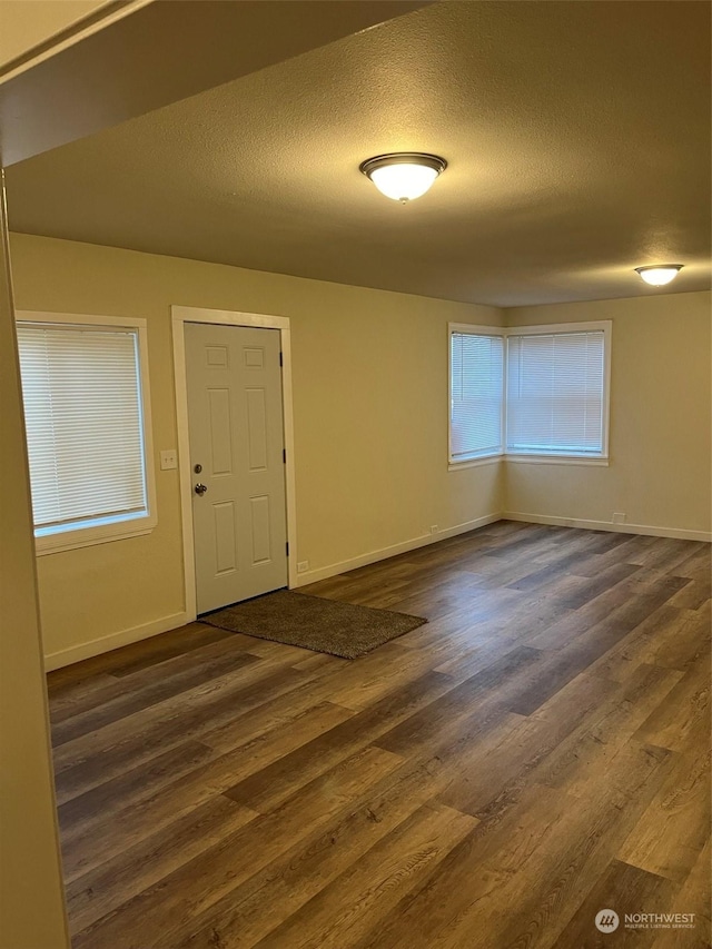 unfurnished room with dark wood-type flooring and a textured ceiling