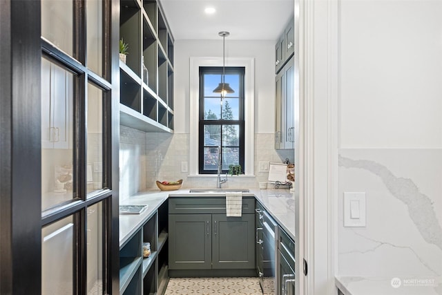 kitchen with light stone countertops, sink, decorative backsplash, and decorative light fixtures