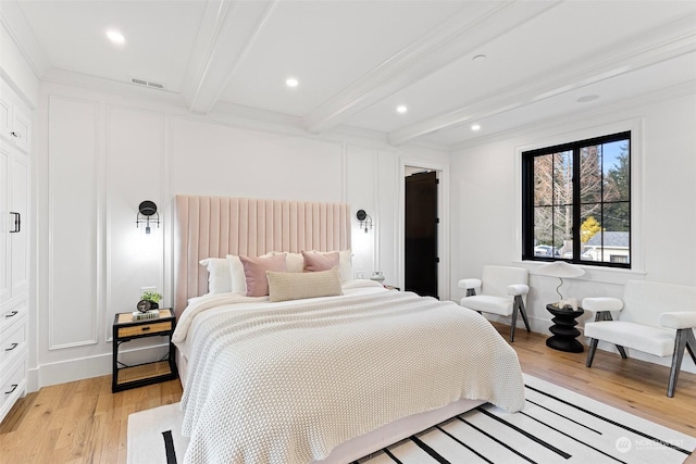 bedroom with crown molding, beam ceiling, and light hardwood / wood-style flooring