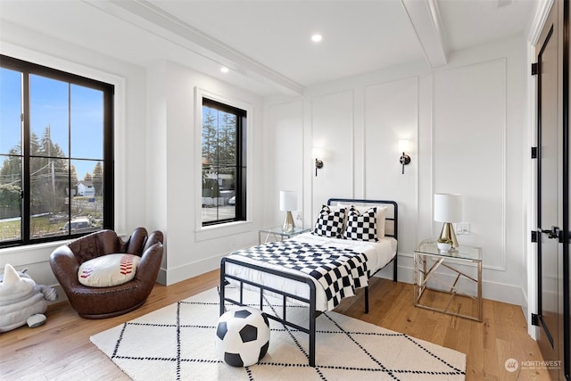 bedroom featuring light hardwood / wood-style floors and beamed ceiling