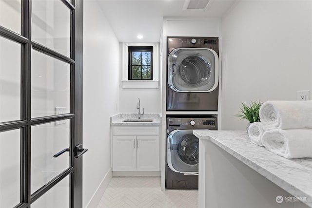 laundry room featuring cabinets, stacked washer and clothes dryer, light parquet flooring, and sink