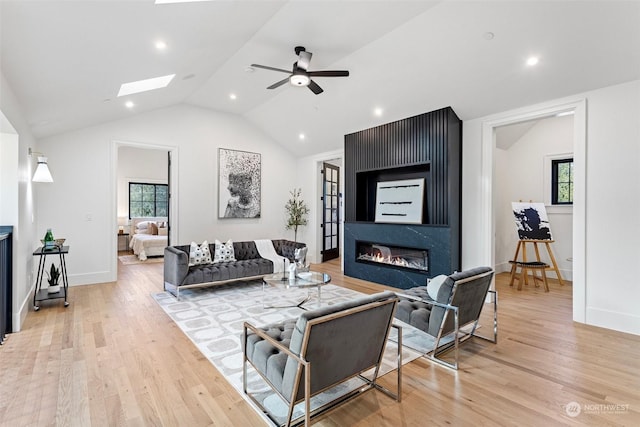 living room with a healthy amount of sunlight, lofted ceiling with skylight, and light hardwood / wood-style flooring